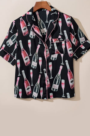 Black silk pajama top with champagne bottle and glass print, pink piping, and short sleeves.