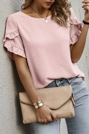 Blush pink polyester blouse with ruffle short sleeves and textured fabric.