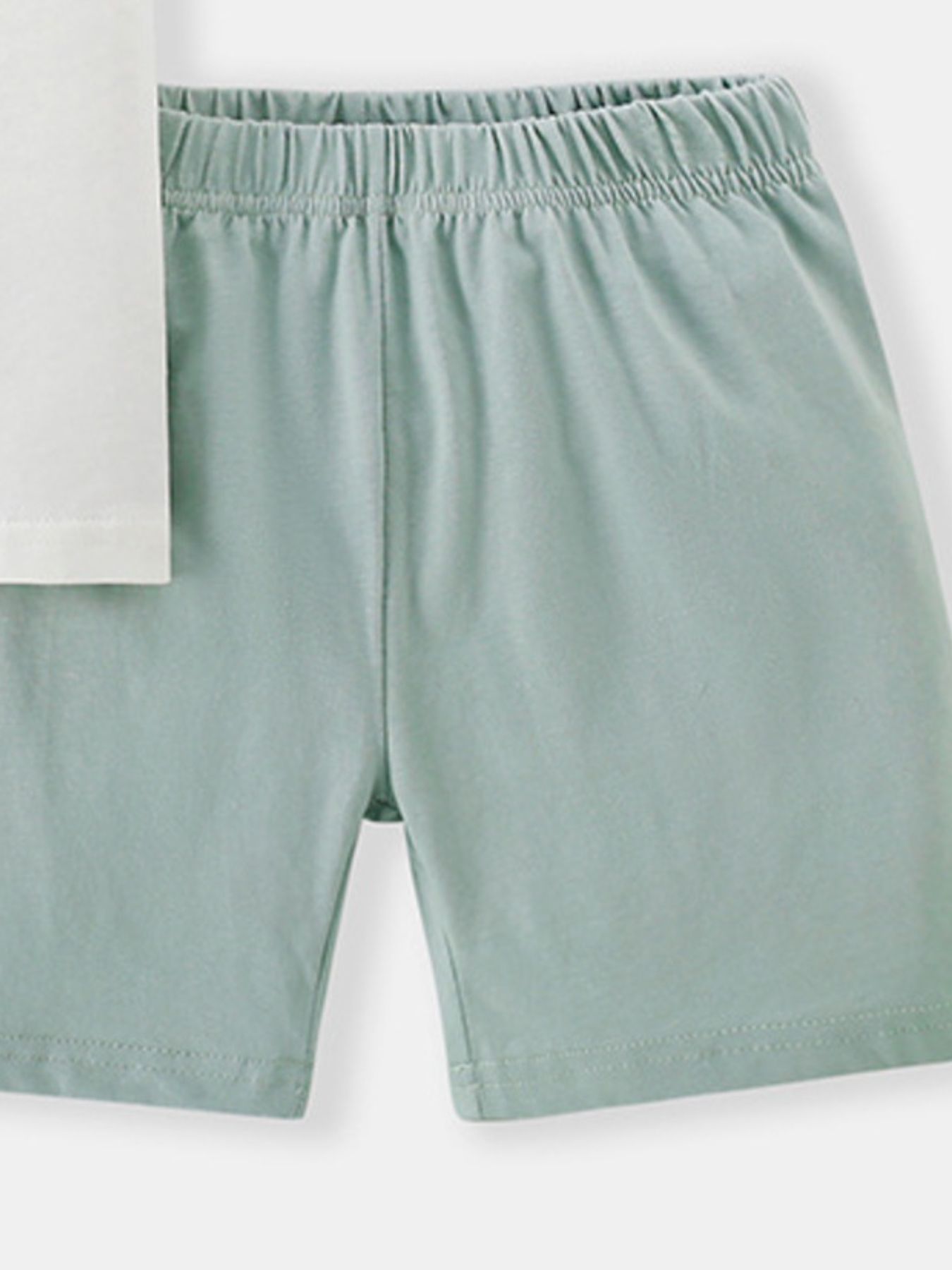 Toddler pale green cotton shorts with elastic waistband and white t-shirt detail.