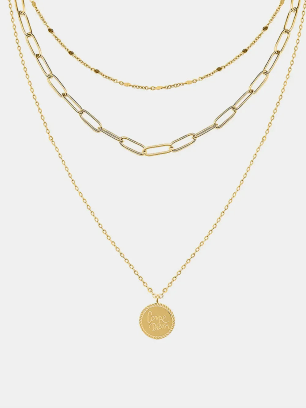 Gold layered chain necklace with a round pendant engraved with "Carpe Diem" text.