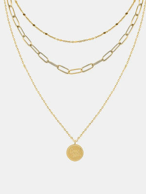 Gold layered chain necklace with a round pendant engraved with "Carpe Diem" text.