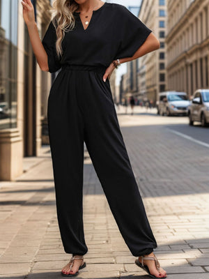 Black drape jumpsuit with short sleeves, V-neck, and elastic waist.