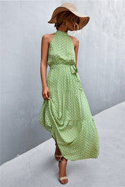 Maxi dress with halter neckline, polka dot print in green, tiered skirt, and tie waist.