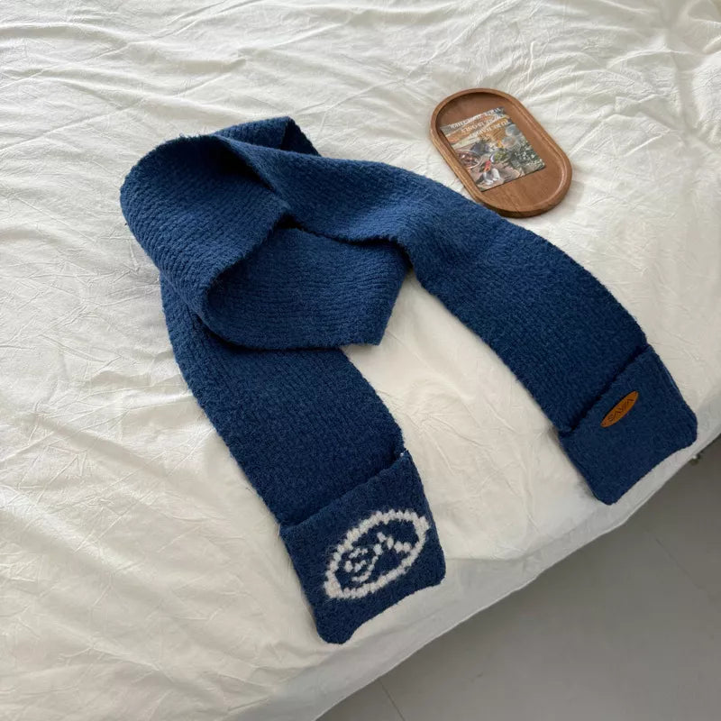 Blue textured knit scarf with pockets featuring white oval logo detail and a brown brand tag.