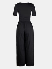 Black textured wide-leg maternity jumpsuit with short sleeves and a subtle elastic waist.