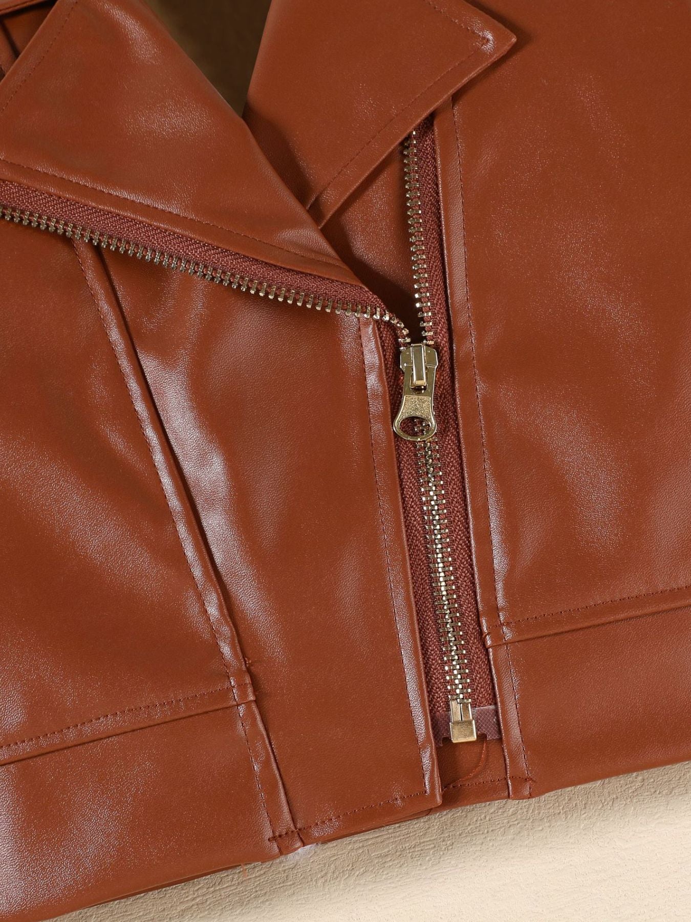 Brown faux leather jacket detail with asymmetrical zipper and collar