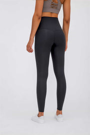 Black high rise leggings with a seamless back view, paired with a sports bra and sneakers.