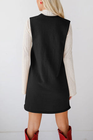 Black knit sweater dress with a deep V-neck, layered over a cream ribbed long-sleeve top.