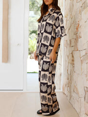 Black silk pajama set with shell print, buttoned shirt and wide leg pants.
