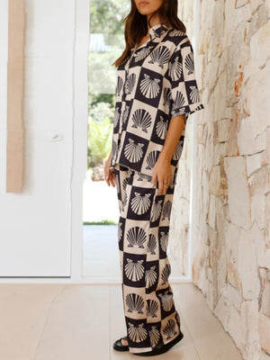 Black silk pajama set with shell print, buttoned shirt and wide leg pants.