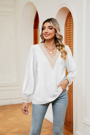 White blouson top with embroidered V-neck trim and puffed sleeves.