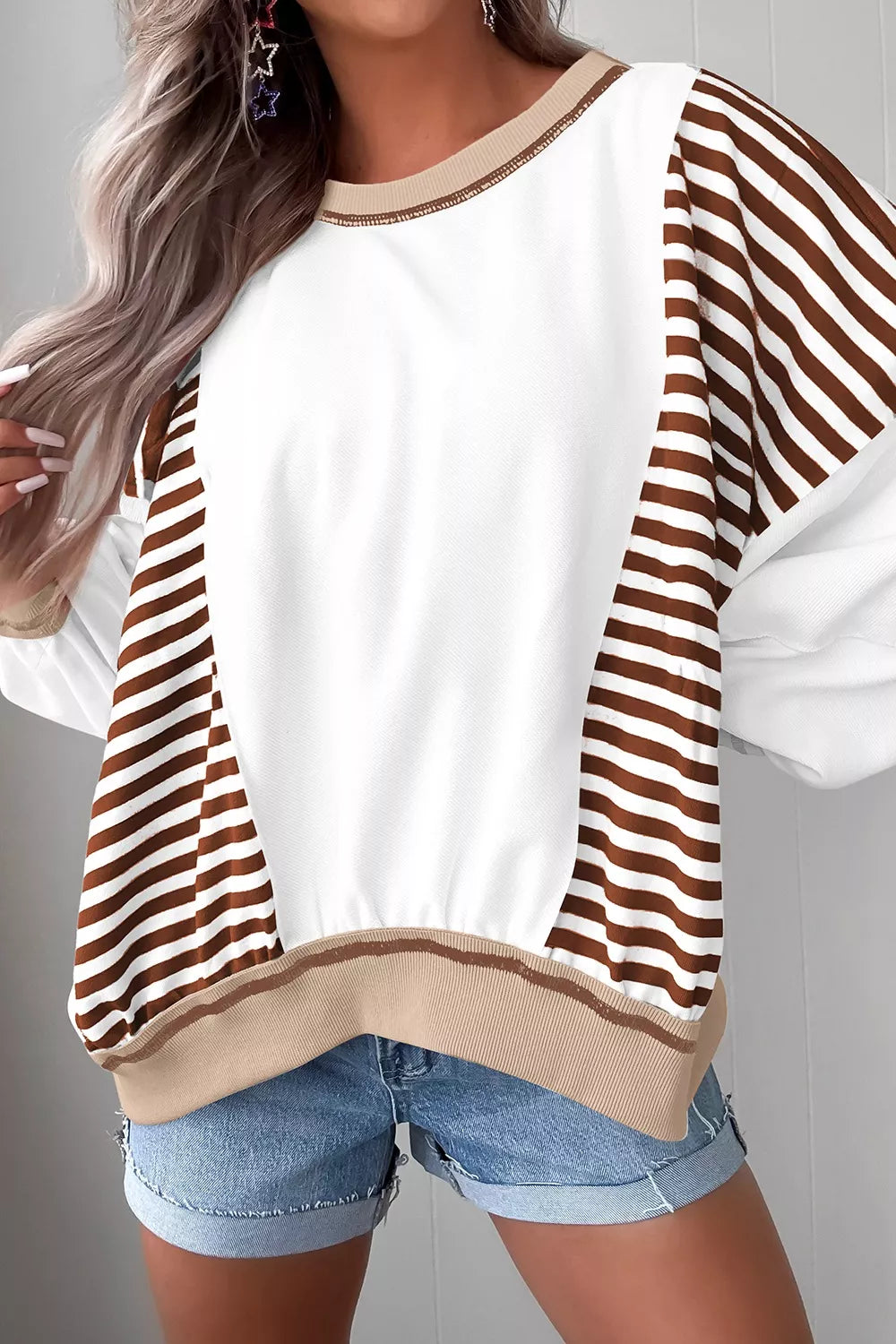 Chic colorblock sweatshirt with white body and brown striped sleeves, contrast stitching detail.