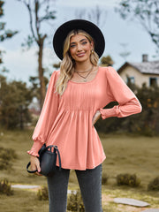 Coral peplum blouse with gathered yoke and smocked cuffs, long sleeves, square neckline.