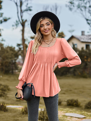 Coral peplum blouse with gathered yoke and smocked cuffs, long sleeves, square neckline.