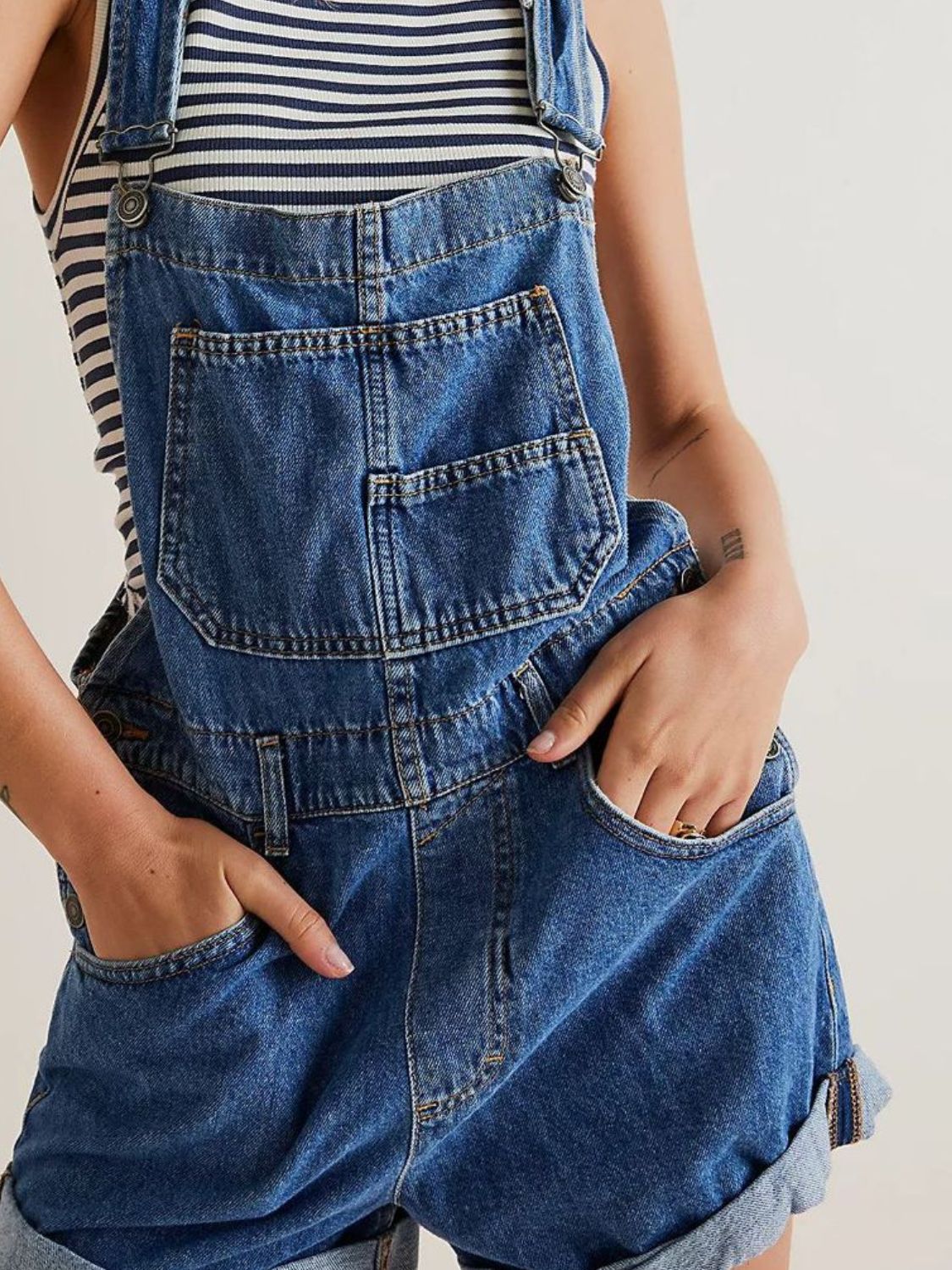Medium wash denim overalls with a bib pocket and cuffed shorts.