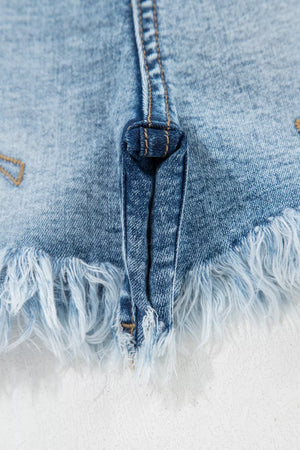 Light wash denim shorts with distressed frayed hem and subtle embroidery detail.
