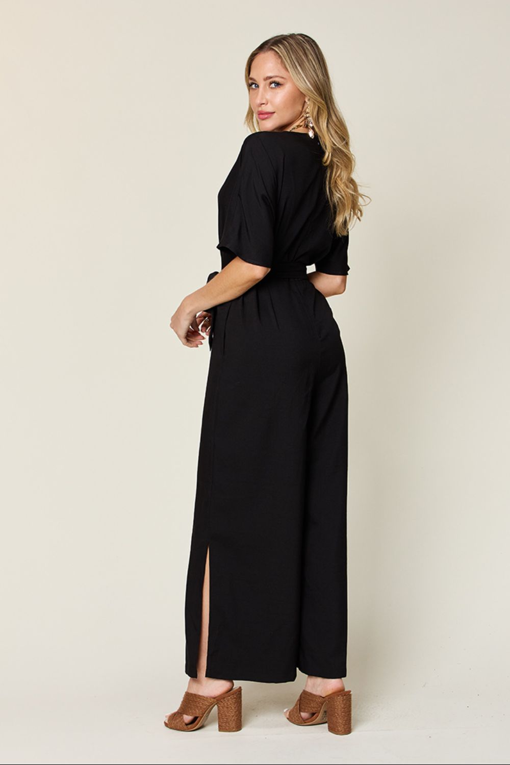 Black wrap jumpsuit with short sleeves, belted waist, and slit wide legs.