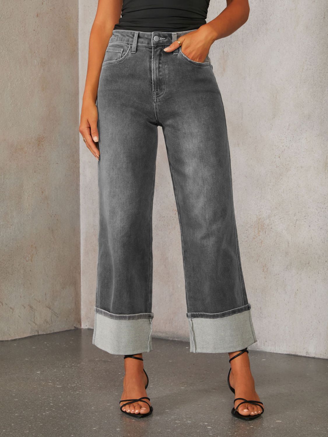 Dark wash denim jeans with wide legs and large folded cuffs.