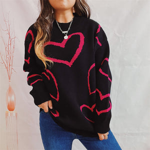 Black acrylic knit sweater with a pink heart outline pattern.