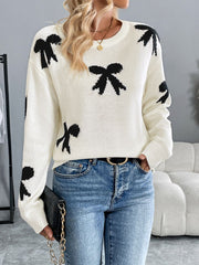 Cream knit crewneck sweater with scattered black bow pattern, long sleeves, and ribbed cuffs.
