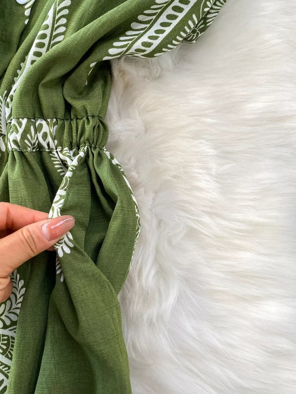 Green buttoned wide leg romper with white pattern detail and elastic waist.