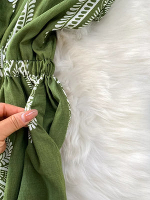 Green buttoned wide leg romper with white pattern detail and elastic waist.