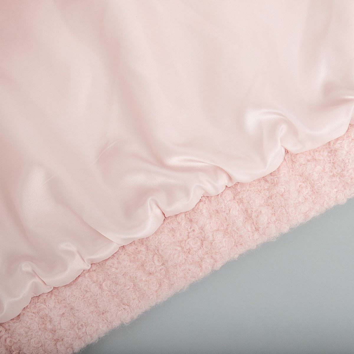 Blush pink bouclé bomber jacket with a smooth satin lining and rounded neckline detail.