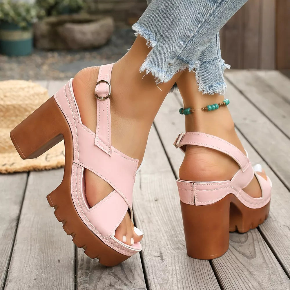 Pink open toe block heel sandals with cross straps and chunky sole.