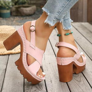 Pink open toe block heel sandals with cross straps and chunky sole.