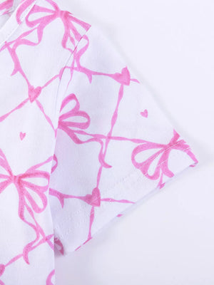 Baby dress with pink bow and heart print on white cotton fabric.