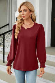 Burgundy blouse with puff sleeves and smocked cuffs.