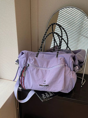 Chic lavender Oxford cloth travel duffel bag with black rope handles and front zip pocket.