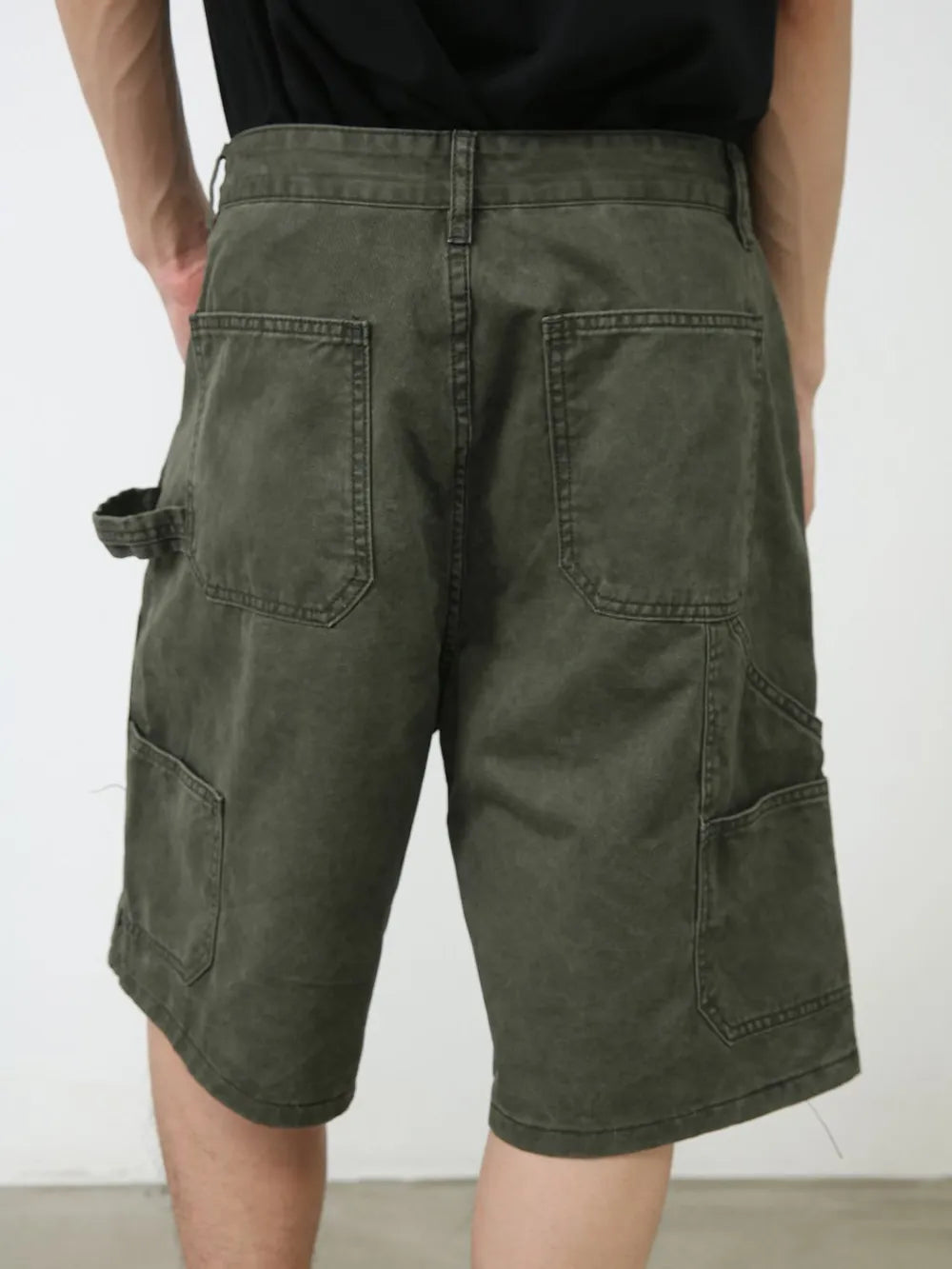 Utility denim carpenter shorts in washed olive with multiple pockets and a tool loop.