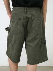 Utility denim carpenter shorts in washed olive with multiple pockets and a tool loop.