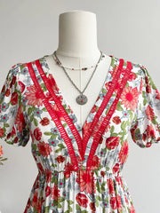 Vibrant floral V-neck midi dress with red trim and short puff sleeves.