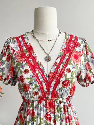 Vibrant floral V-neck midi dress with red trim and short puff sleeves.