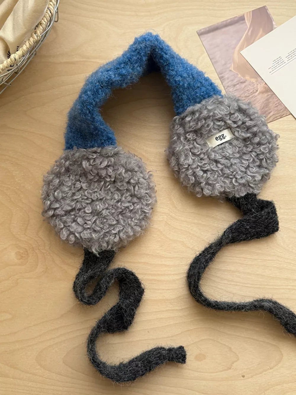 Plush sherpa earmuffs in gray with a blue textured headband and dark gray ties.
