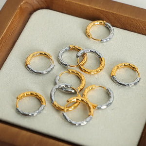 Textured two-tone huggie hoop earrings in gold with a hammered finish.