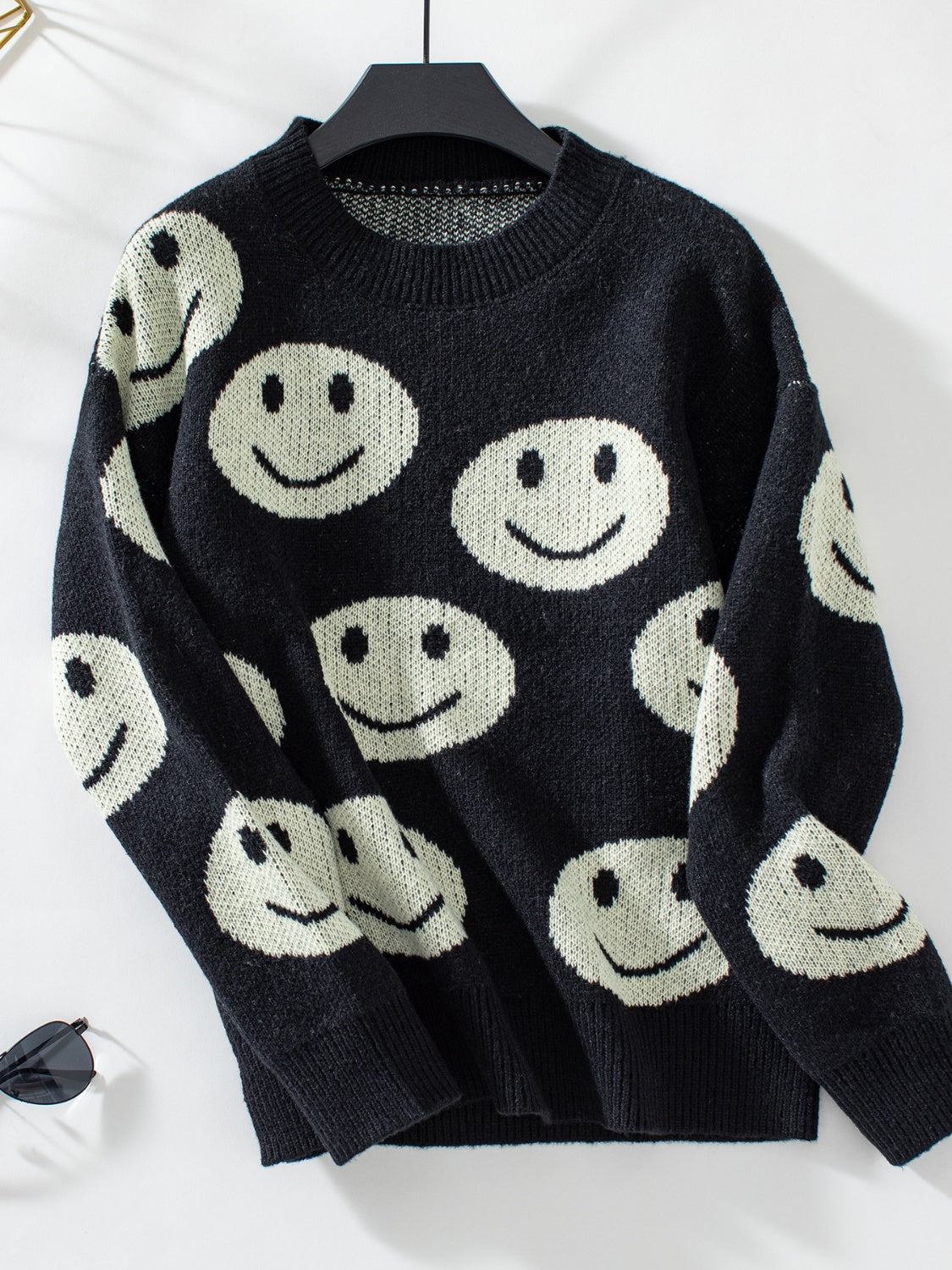 Black knit sweater with allover white smiley face intarsia pattern and crew neck.