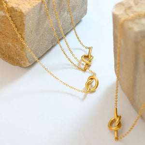 Gold tied bar pendant necklace with delicate chain and knot detail