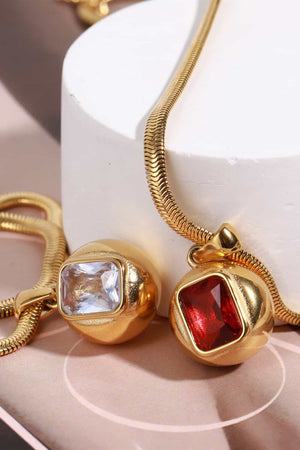 Gold necklace with orb pendants featuring square stones in transparent and deep red.
