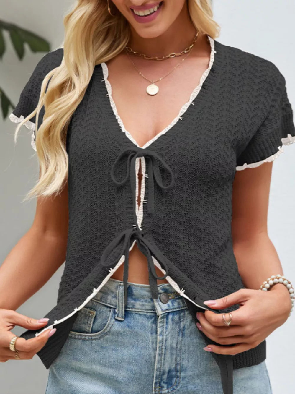 Black knit tie-front cardigan with white trim and short sleeves