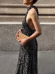 Black and white polka dot halter maxi dress with a high neckline and open sides.