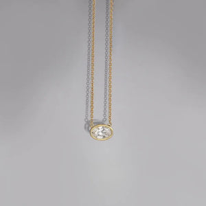 Bezel-set oval diamond solitaire necklace on a delicate 18K gold-plated chain.