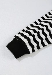 Black and white striped blouse with ribbed cuffs and wavy stripe pattern.