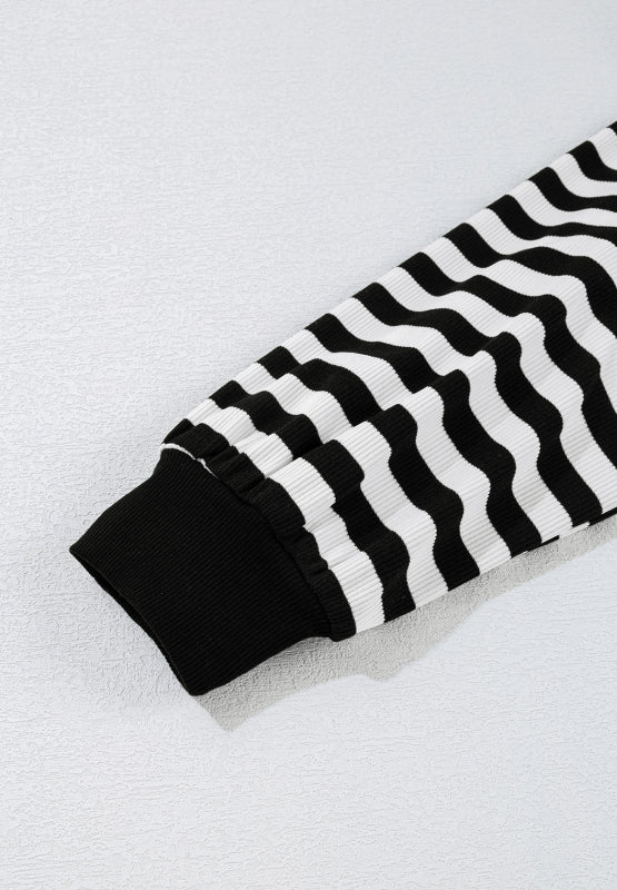 Black and white striped blouse with ribbed cuffs and wavy stripe pattern.