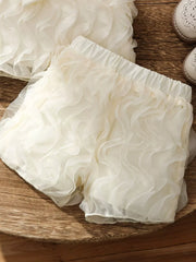 Cream ruffled baby shorts with elastic waist and sheer overlay.