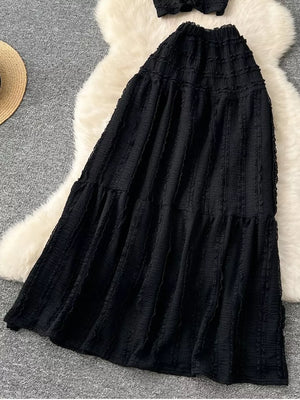 Black textured two-piece set with ruffled details and tiered skirt.