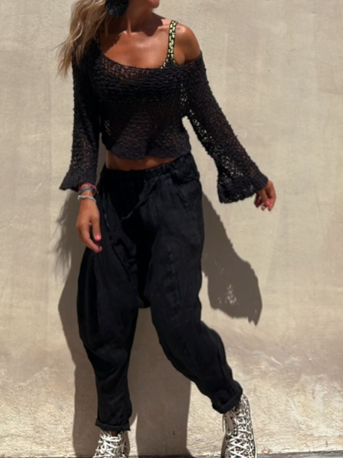 Black asymmetric crochet crop top with bell sleeves and scoop neck.