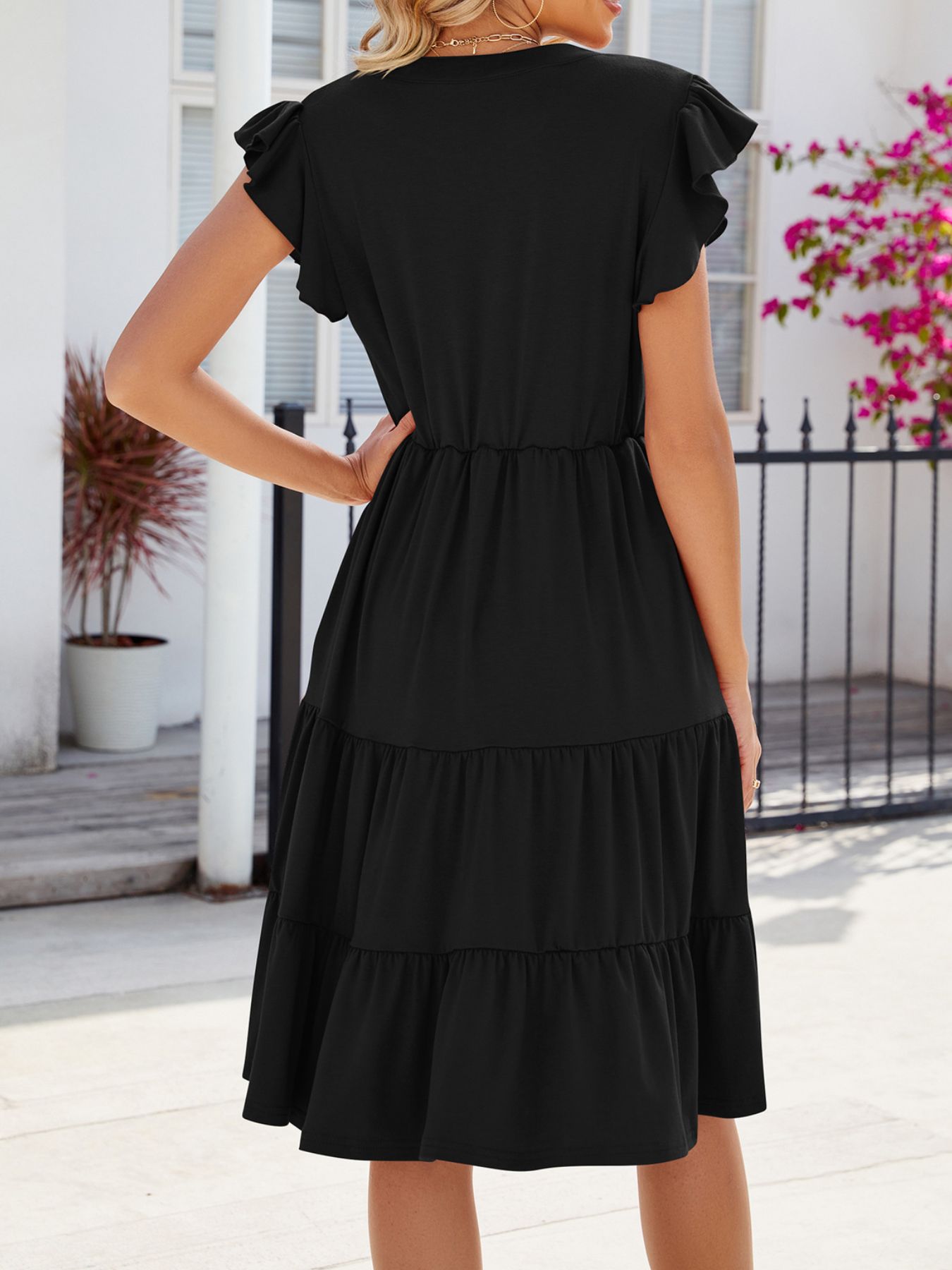Black ruffled midi dress with tiered skirt and flutter sleeves.